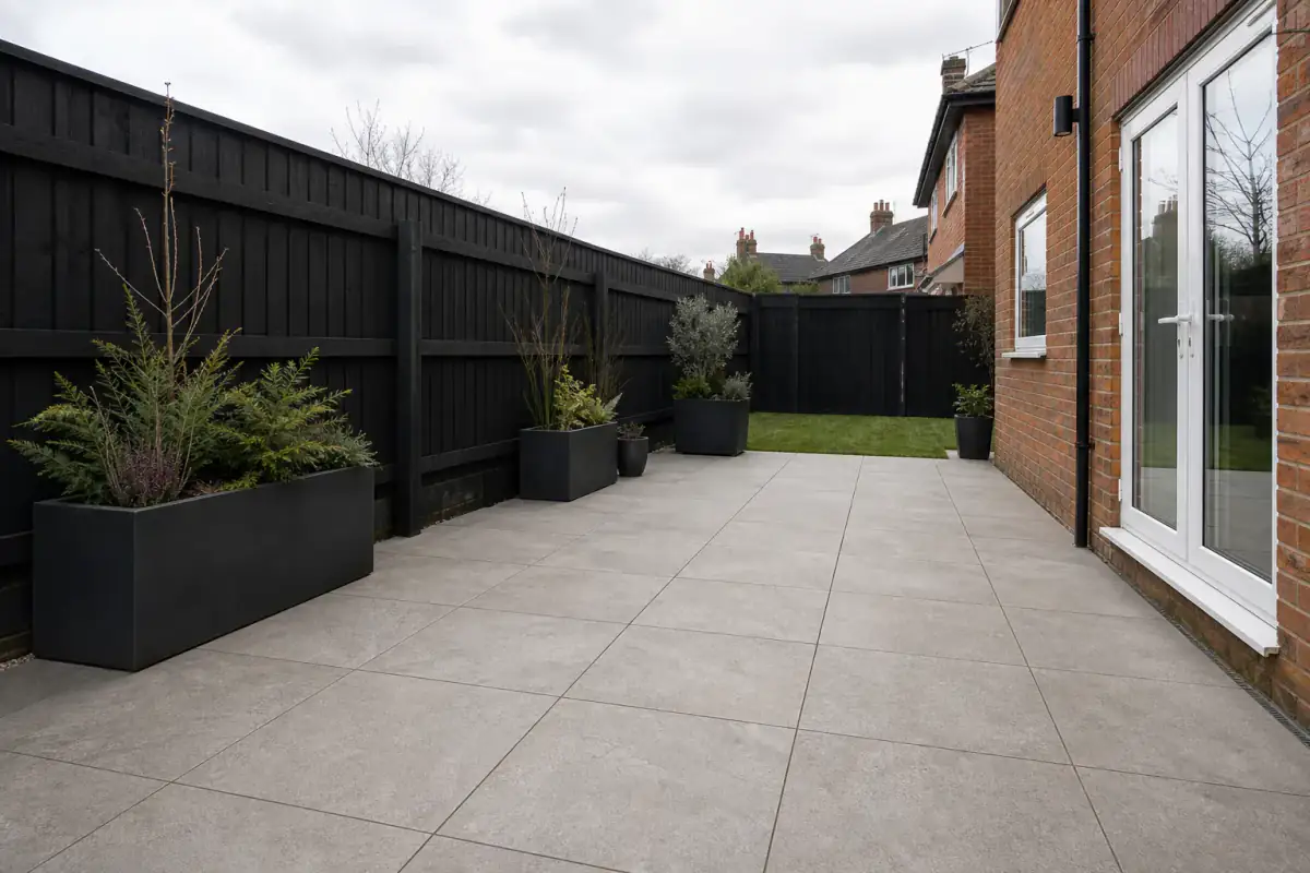 A practical warm-grey patio beside a red-brick UK home